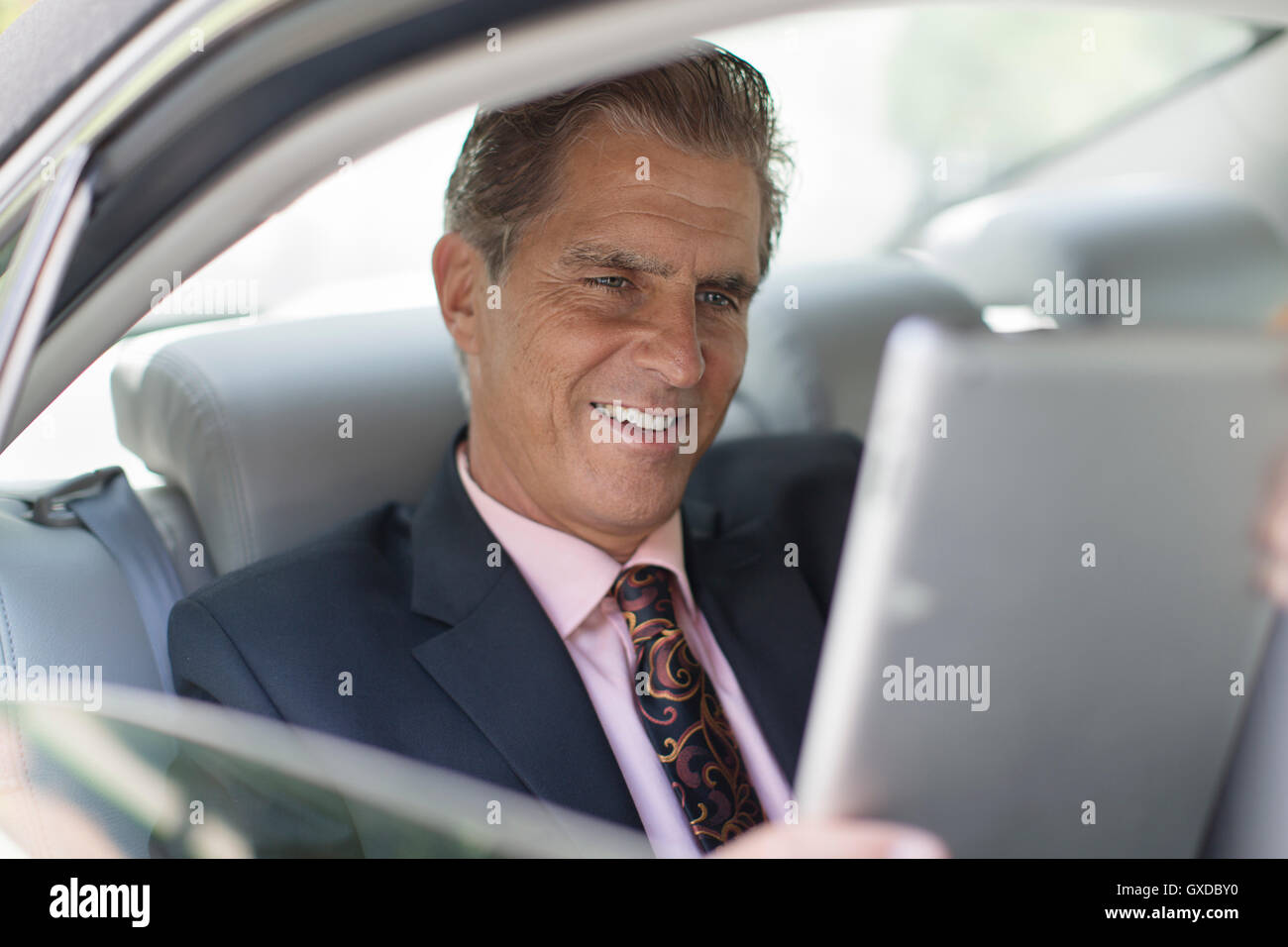 Mature businessman, au dos de la voiture, using digital tablet Banque D'Images