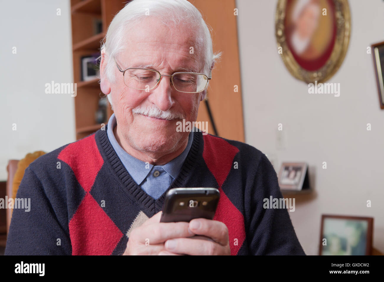 Senior man using mobile phone at home Banque D'Images