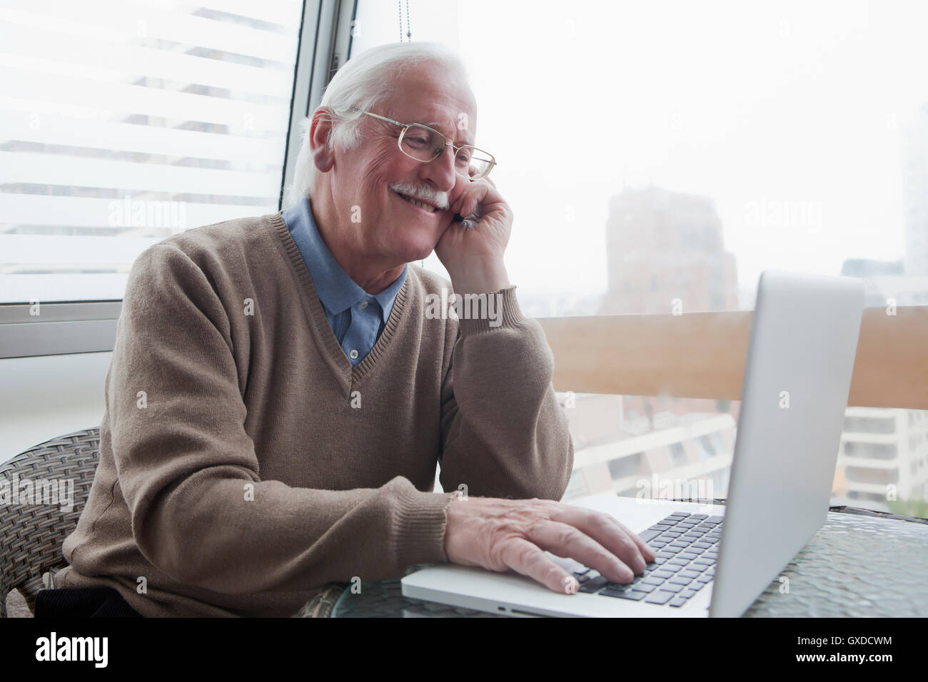 Senior man using mobile phone and laptop at home Banque D'Images