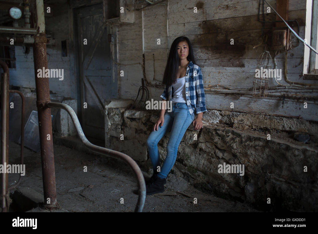 Portrait of teenage girl leaning against wall hangar poussiéreux Banque D'Images