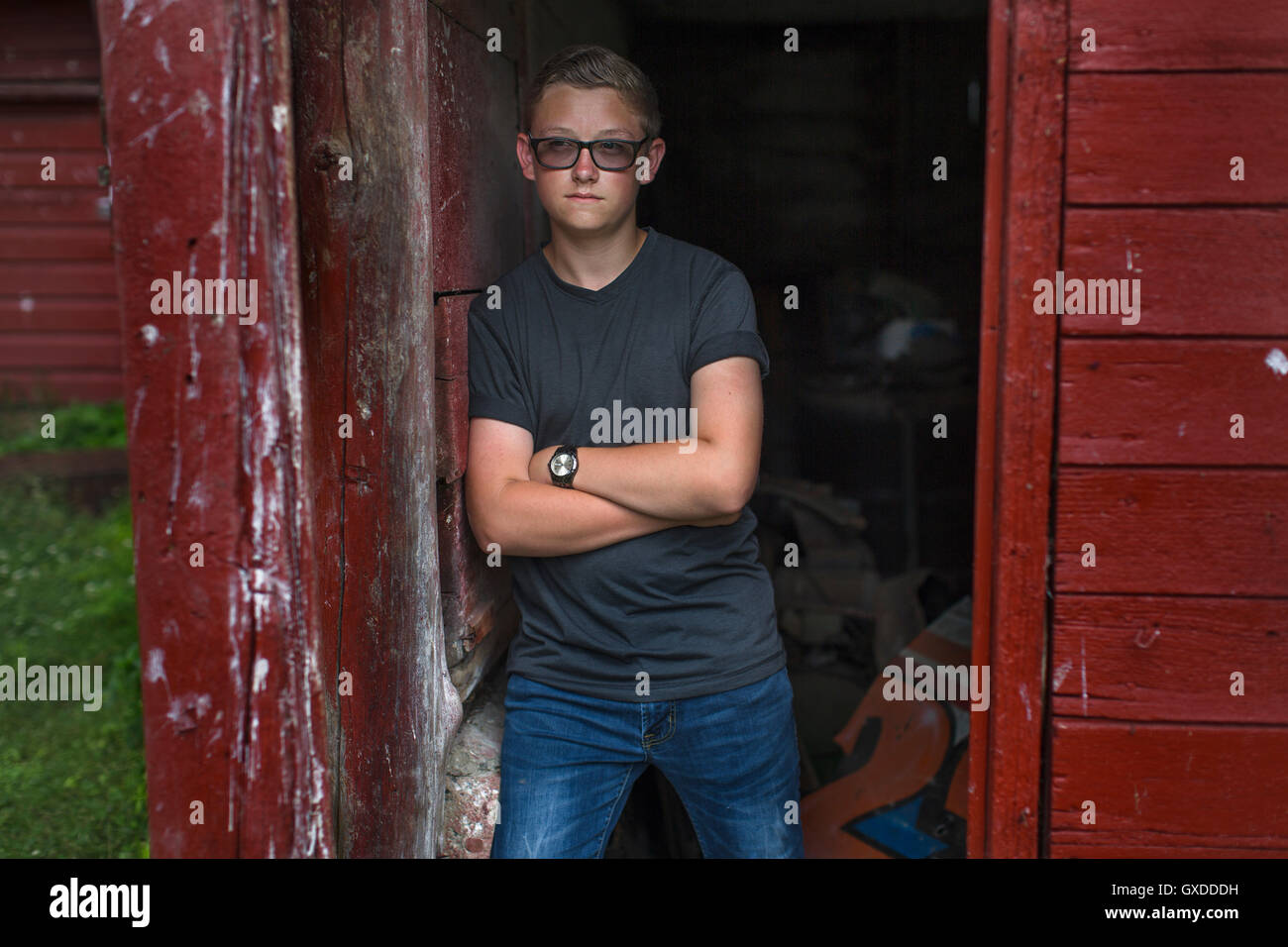 Portrait of teenage boy portant des lunettes teintées appuyé contre la porte Banque D'Images