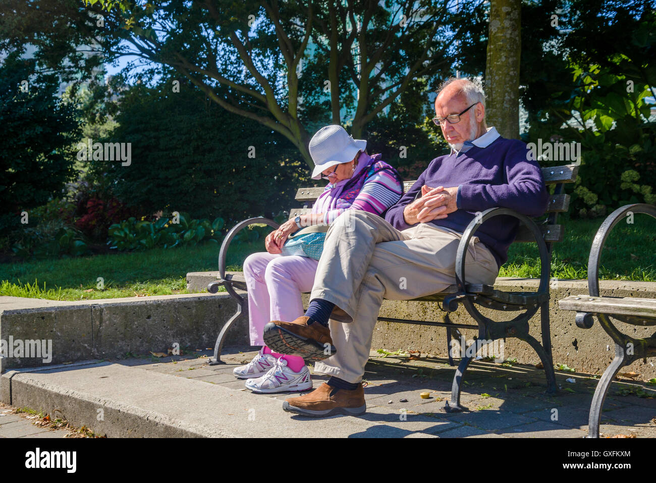Vieux couple endormi sur le banc de parc Banque D'Images