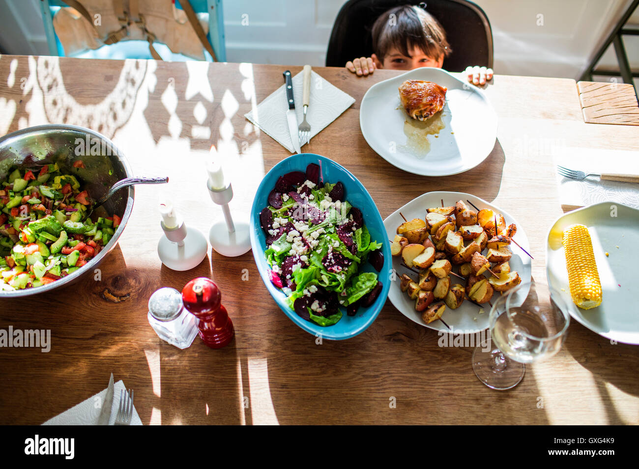 Mixed Race boy se cacher derrière le tableau avec des aliments Banque D'Images