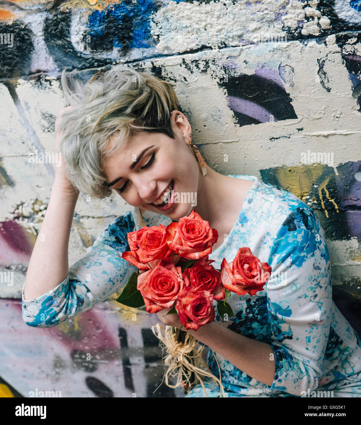 Laughing Caucasian woman au mur de graffiti holding Flowers Banque D'Images