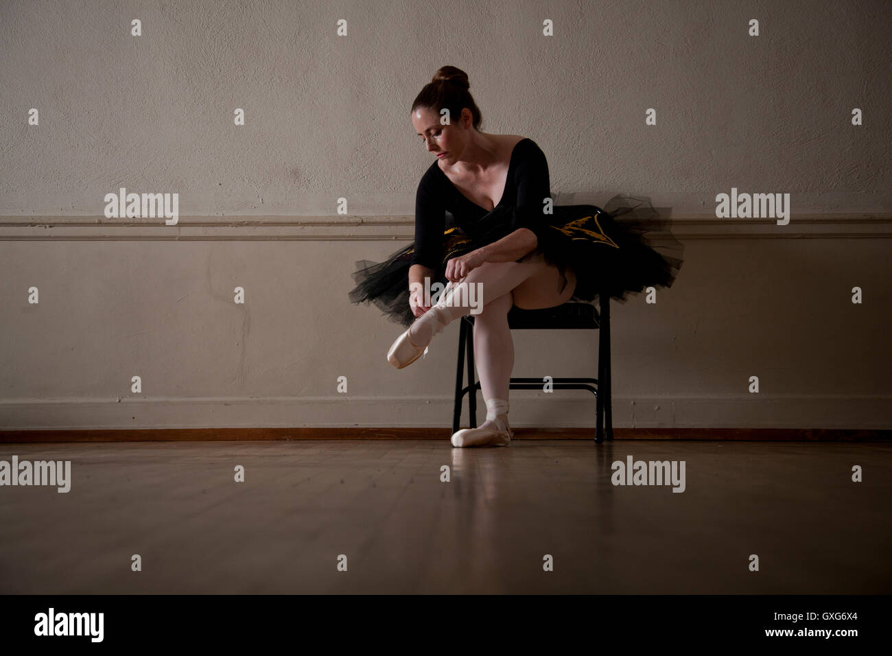 Caucasian ballerina sitting on chair lier chaussures de ballet Banque D'Images