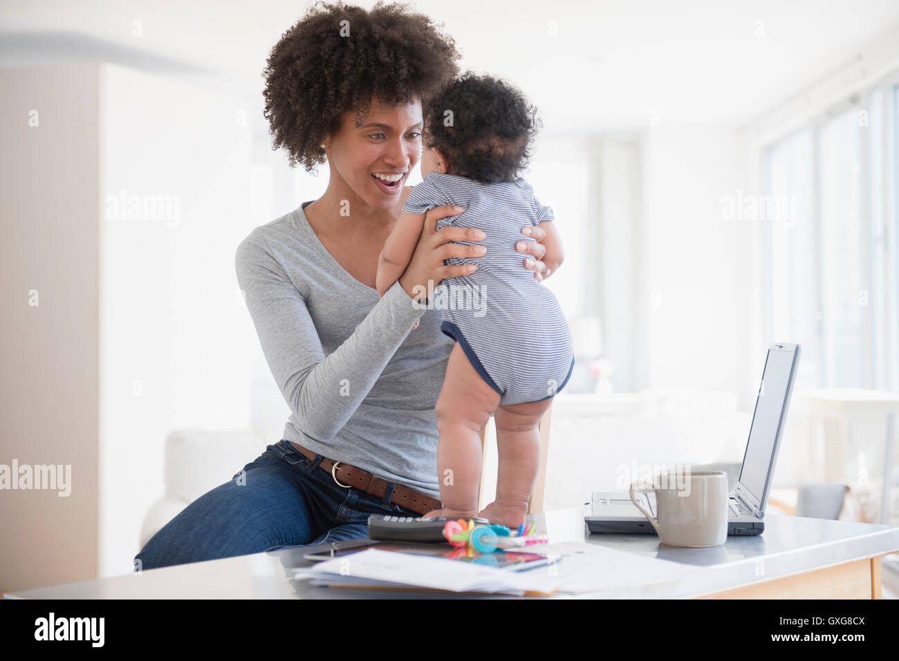 Mother helping baby son stand sur le comptoir Banque D'Images