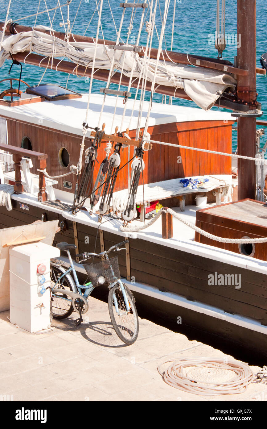 L'approvisionnement en eau et électrique piédestal, vélo et une corde sur le quai, à côté du bateau en bois amarré. Banque D'Images