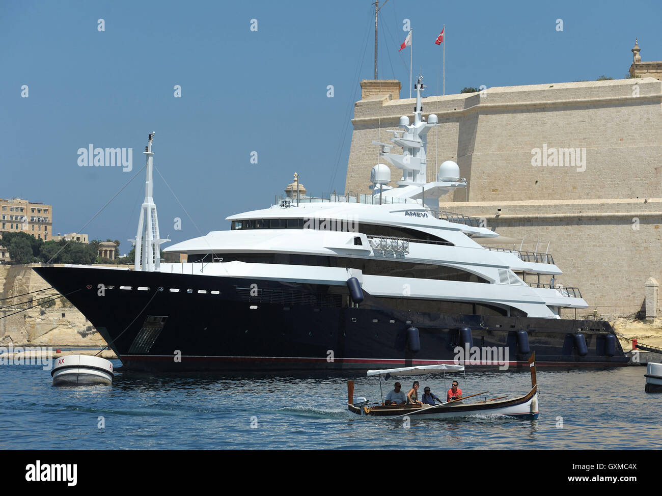 Un luzzu traditionnel passe un luxe superyacht à Grand Harbour Marina, Vittoriosa, La Valette, Malte Banque D'Images