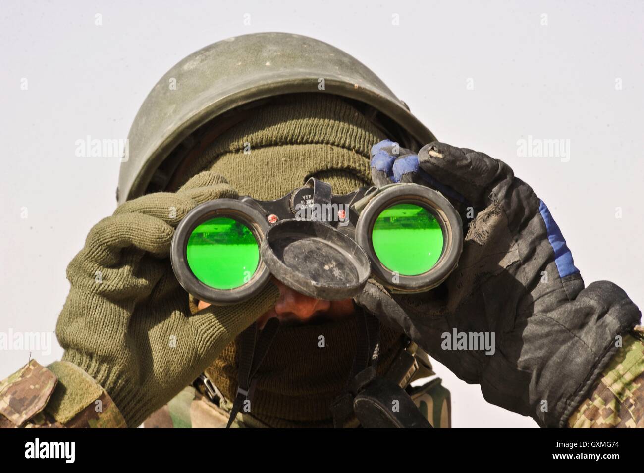 Soldat de l'Armée nationale afghane regarde à travers des jumelles lors d'une patrouille de l'opération araignée de l'Helmand, 16 février 2010 à Badula Quip, province de Helmand, en Afghanistan. Banque D'Images