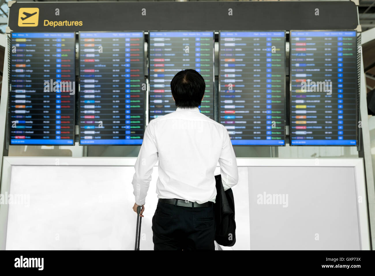 Business Travel Concept - Asian man avec assurance en attente de voyager dans l'aéroport près de horaire de vol. Banque D'Images