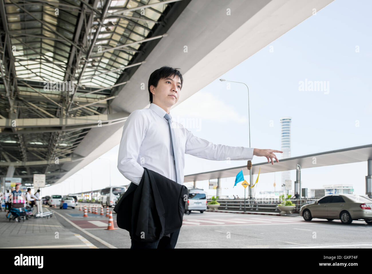Business Travel Concept - Young Asian business man appelant taxi à l'aéroport. Banque D'Images