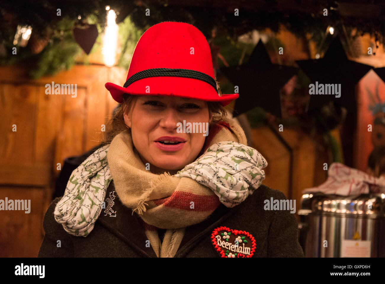 Membre de l'équipe du bar portant des chapeaux à plumes gluhwein bavarois servant à l'une des nombreuses cabanes de bois à la Munich Christma Banque D'Images