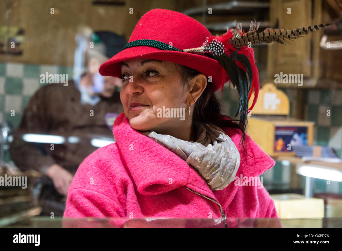 Membre de l'équipe du bar portant des chapeaux à plumes gluhwein bavarois servant à l'une des nombreuses cabanes de bois à la Munich Christma Banque D'Images