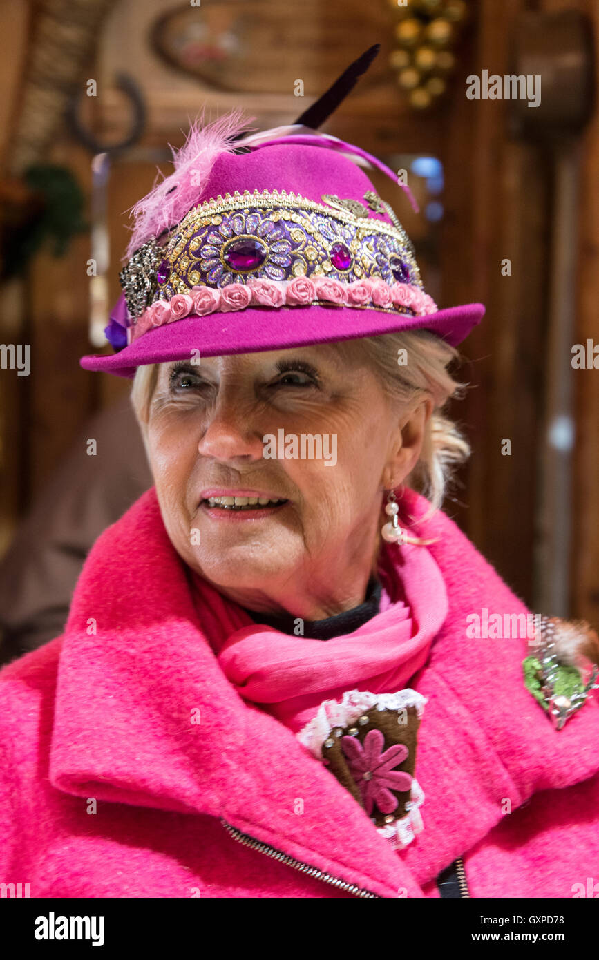 Membre de l'équipe du bar portant des chapeaux à plumes gluhwein bavarois servant à l'une des nombreuses cabanes de bois à la Munich Christma Banque D'Images