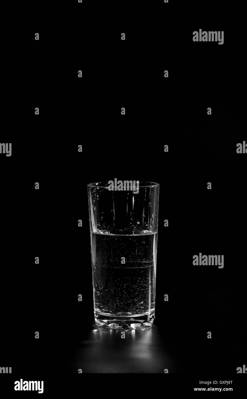 Verre rempli avec de l'eau claire sur un fond foncé permanent Banque D'Images