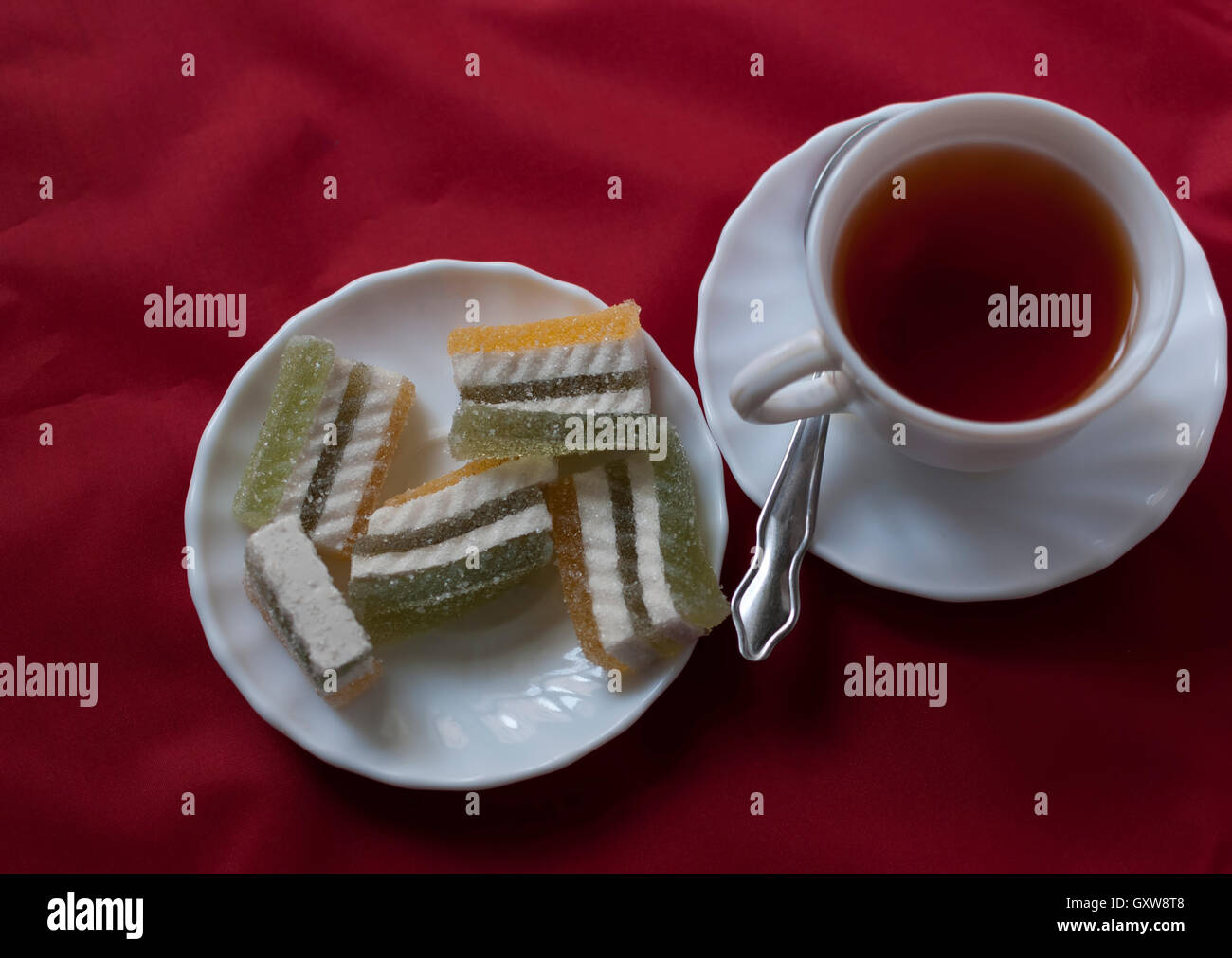 Plateau d'hibiscus et d'une assiette de gelée multicolore sur un fond en tissu rouge Banque D'Images