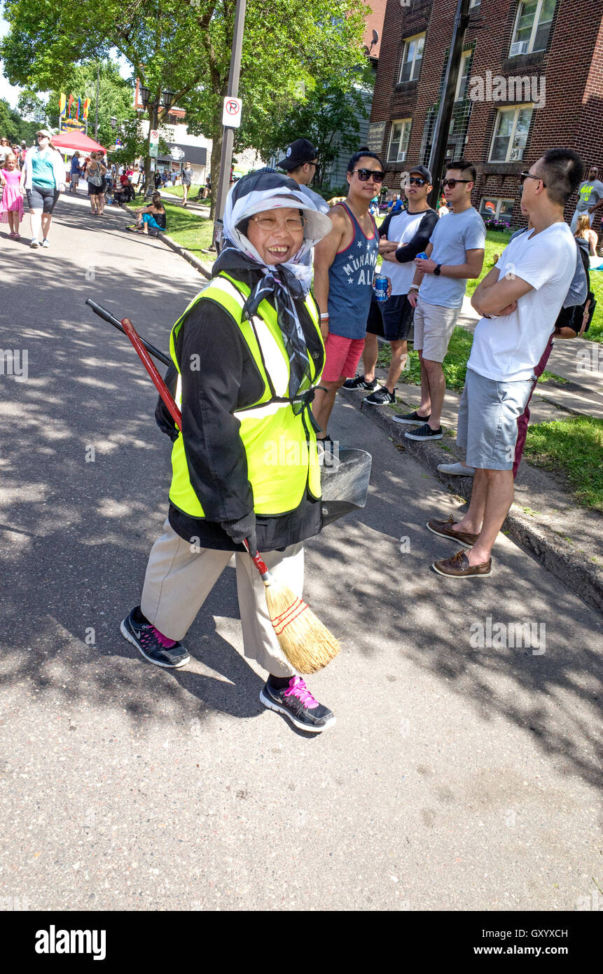 Femme Hmong avec balai, pelle et safety jacket ramasser les déchets au cours Grand Old jour foire de rue. St Paul Minnesota MN USA Banque D'Images