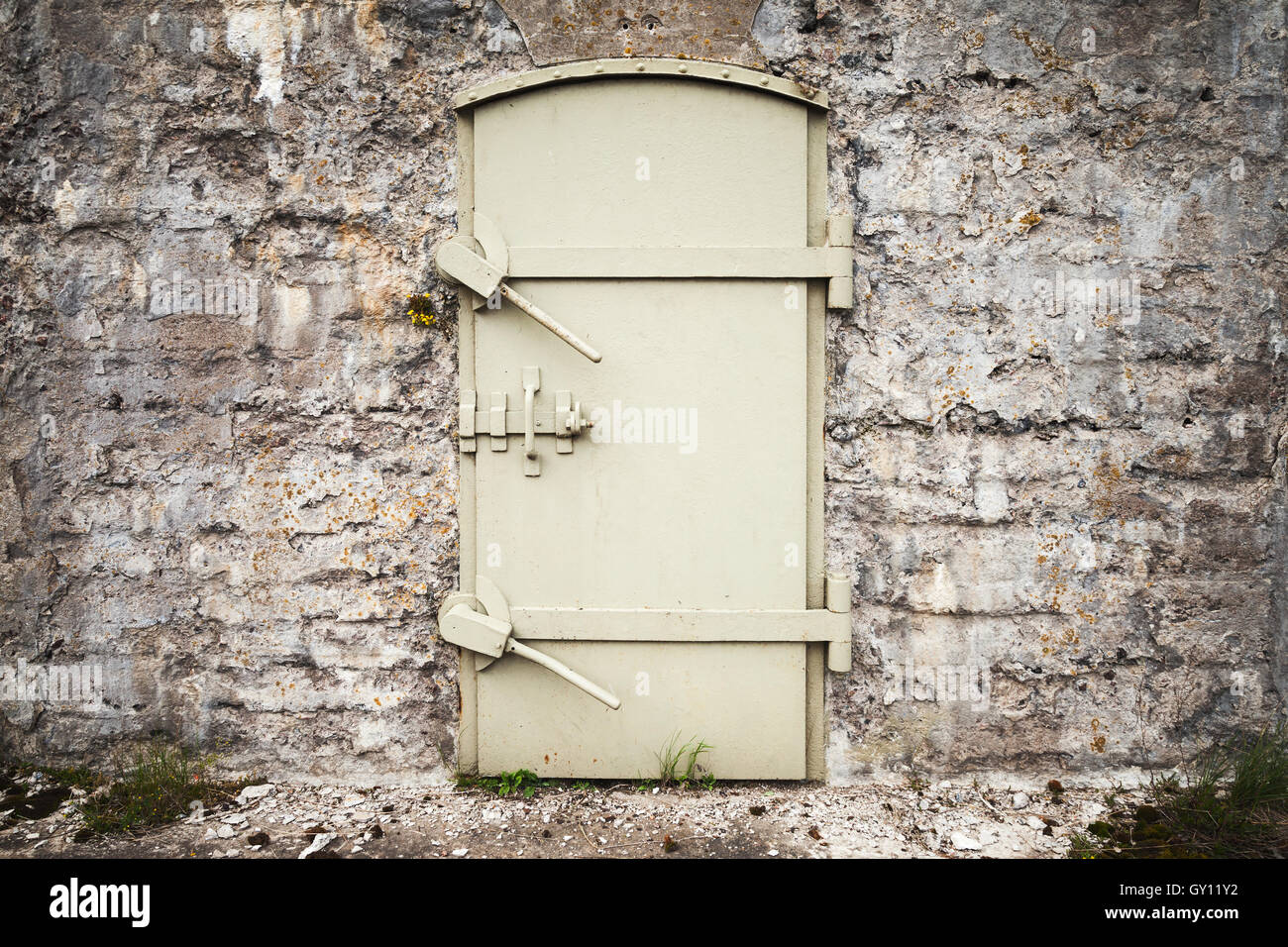 Porte en métal massif verrouillée dans le vieux mur de fortification, texture d'arrière-plan Banque D'Images