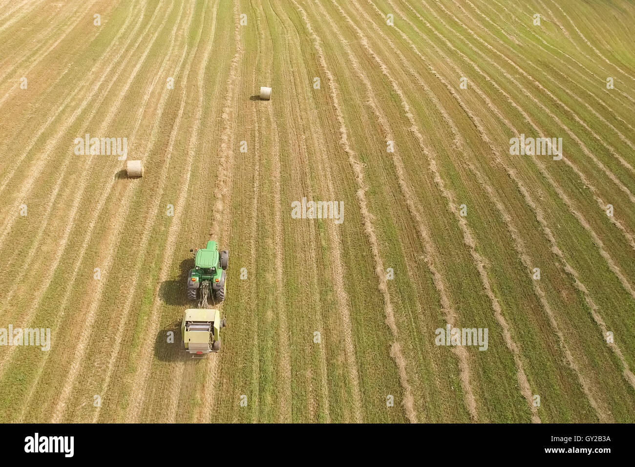 Vue aérienne de tracteur avec le matériel roulant de la ramasseuse-presse à balles de paille sur le champ moissonné Banque D'Images