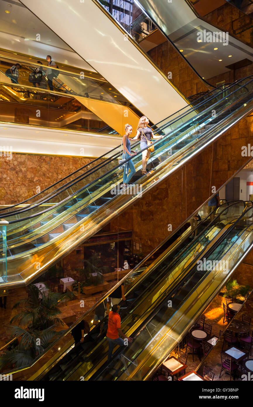 NEW YORK - 3 septembre 2016 : les visiteurs monter les escaliers mécaniques en laiton en miroir dans l'atrium de marbre rose la Trump Tower. Banque D'Images