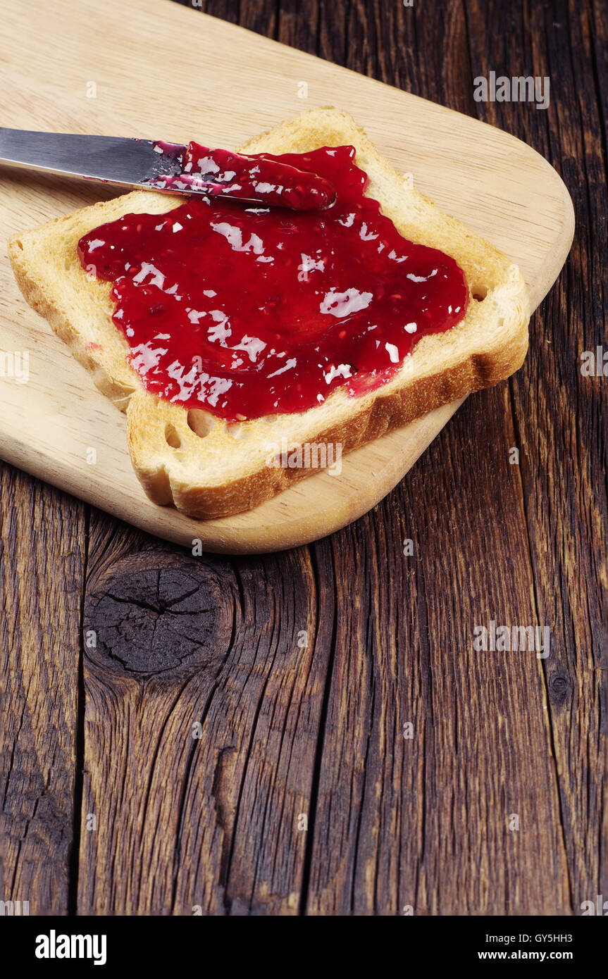 Toast avec confiture de framboises sur table en bois vintage Banque D'Images
