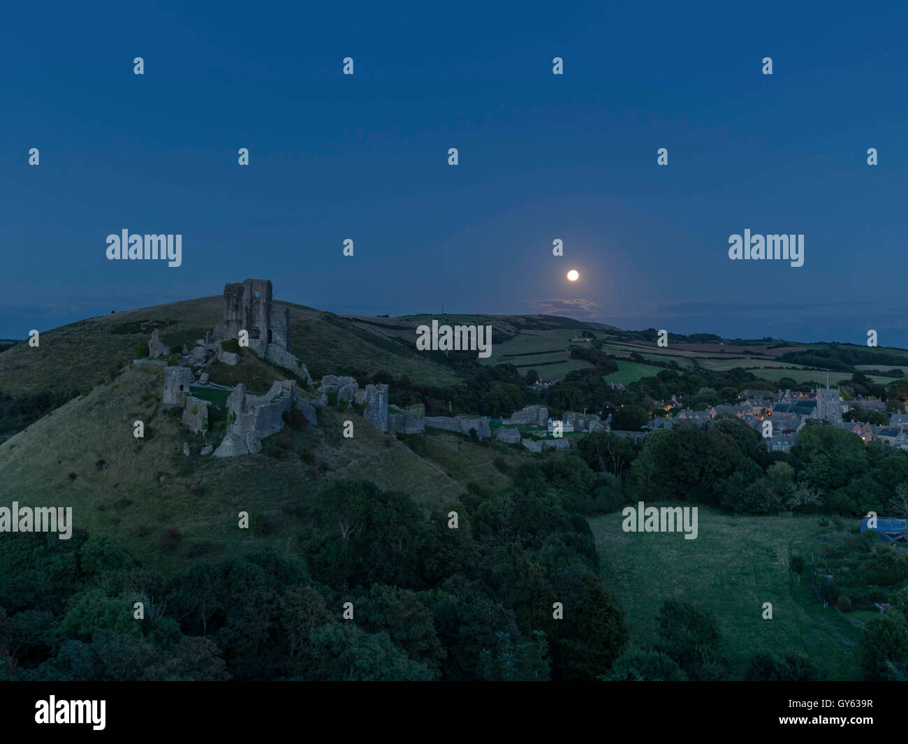 Représentant du paysage la fin de l'été Harvest Moon rise à Corfe Castle, Dorset, UK Banque D'Images