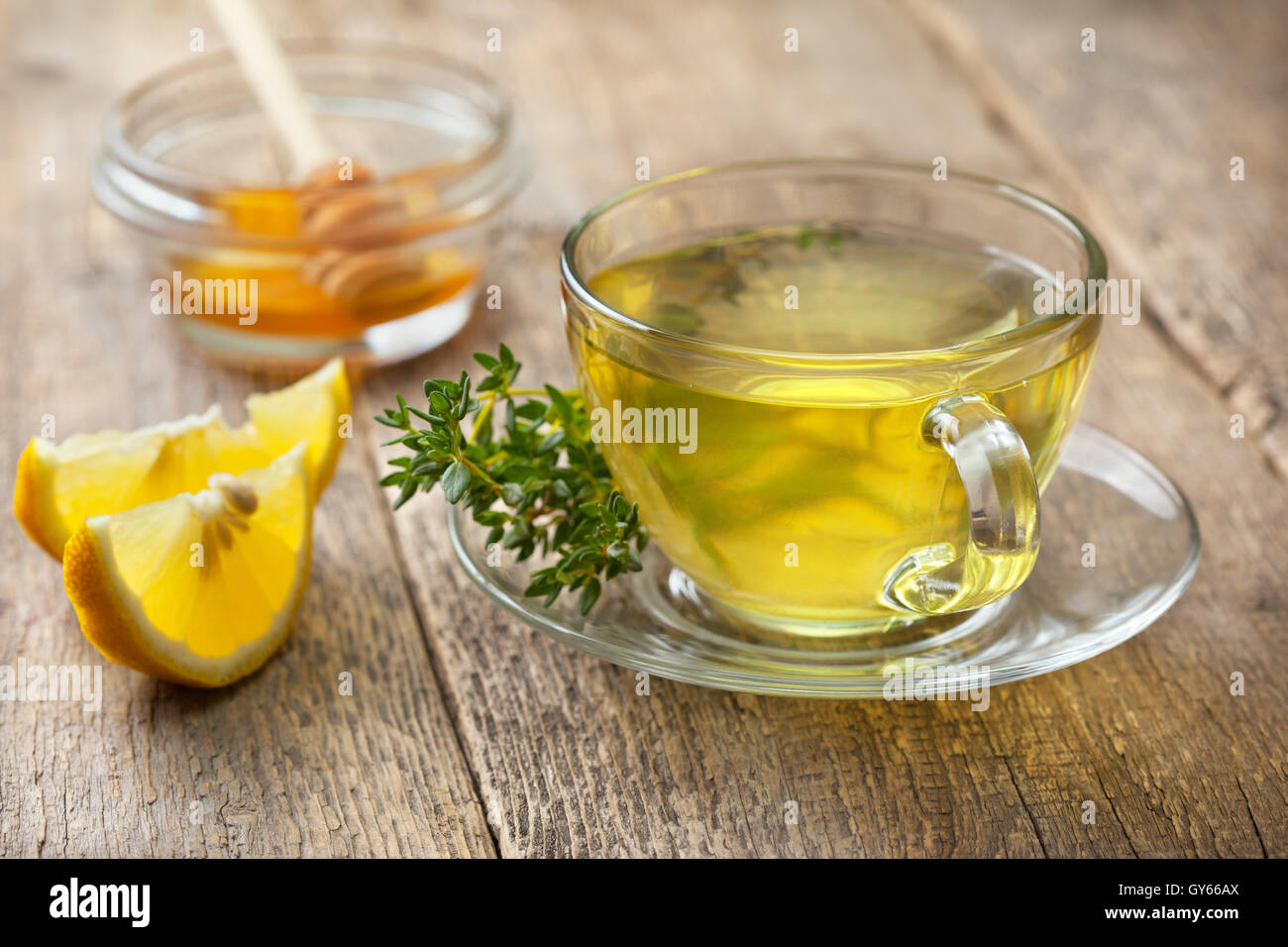 Thé de thym dans du verre tasse, branche de thym frais, tranches de citron, le miel sur le vieux fond de bois Banque D'Images