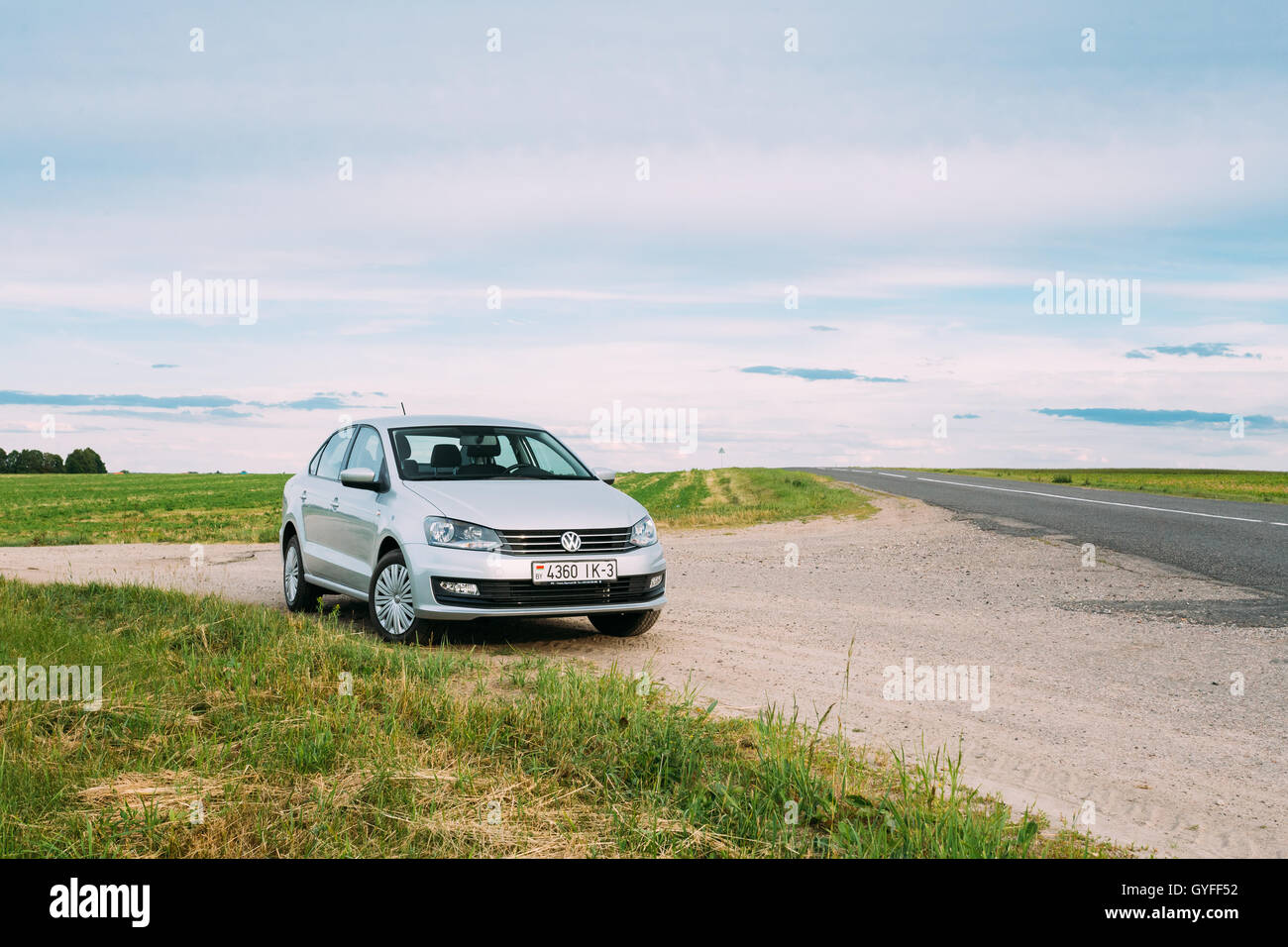 Gomel, Bélarus - 13 juin, 2016 : Volkswagen Polo Parking voiture sur l'accotement des routes de campagne, sur fond de champs de printemps vert Banque D'Images