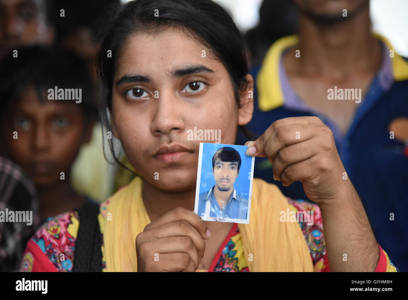Parent d'un employé d'usine du Bangladesh contient jusqu'sa photo à un bâtiment où leurs corps ont été apportés après une explosion Banque D'Images