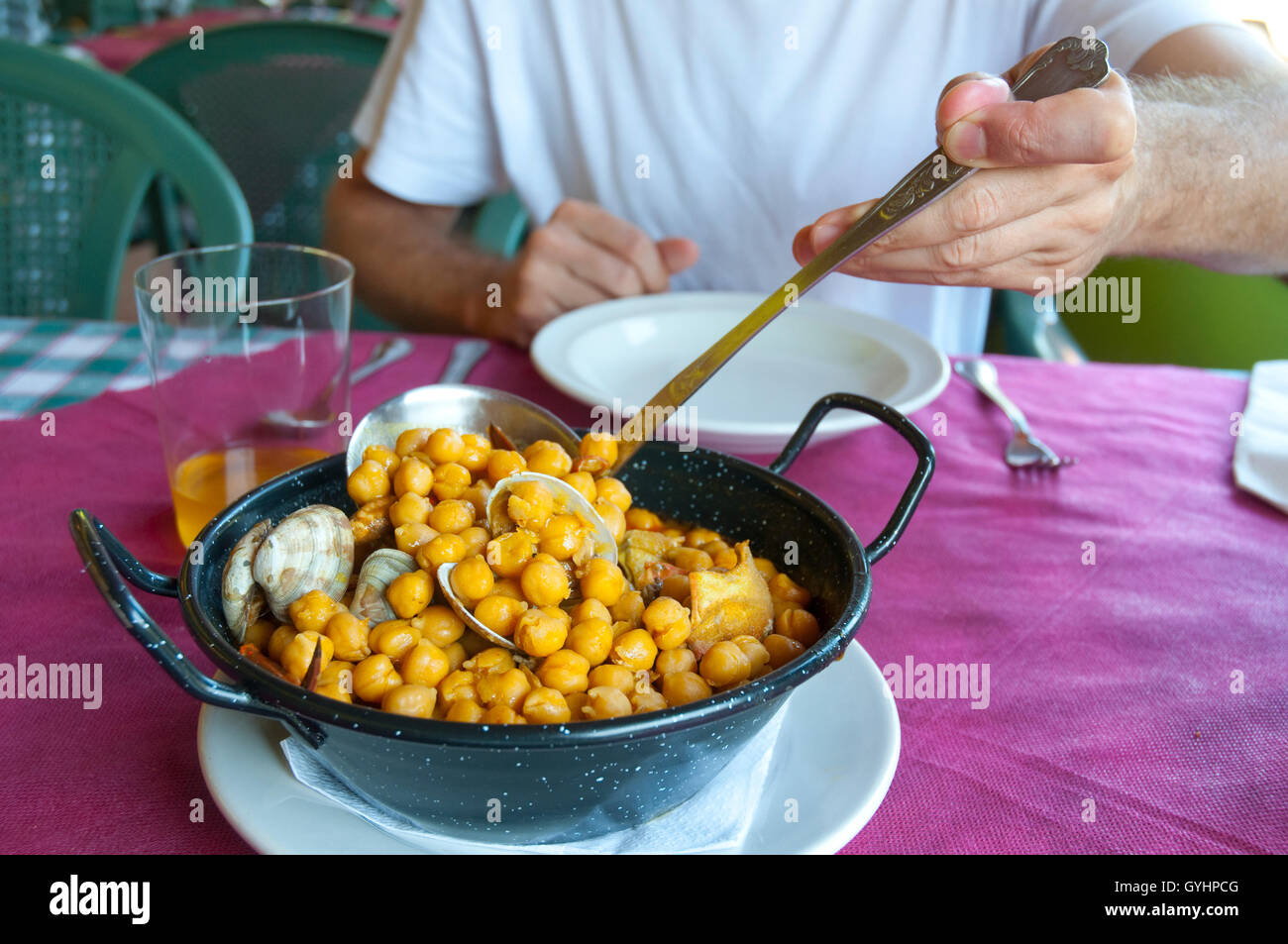 La main de l'homme servant de pois chiches avec des fruits de mer. Voir de très près. Banque D'Images