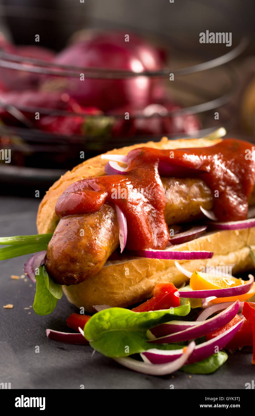 Saucisse avec bun, légumes et ketchup Banque D'Images