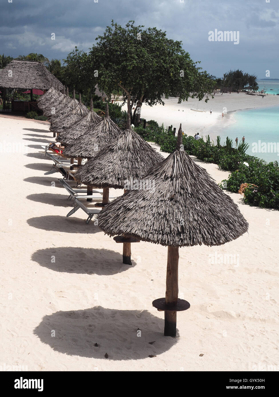 Vue plongeante sur une ligne de soleil parasols en chaume casting shadows sur une plage de sable blanc Banque D'Images