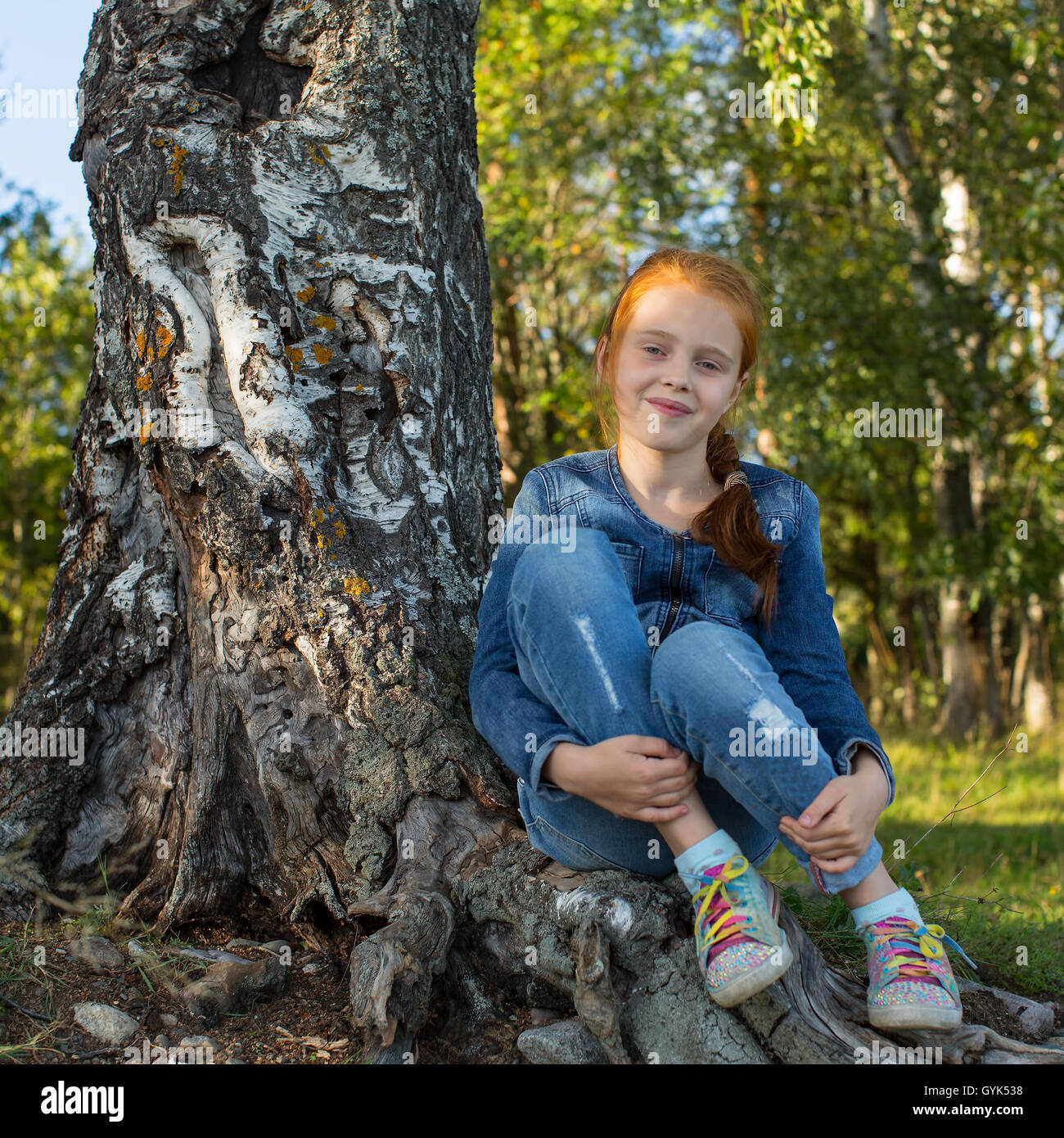 Petite fille assise dans les bois près de Birch. Banque D'Images