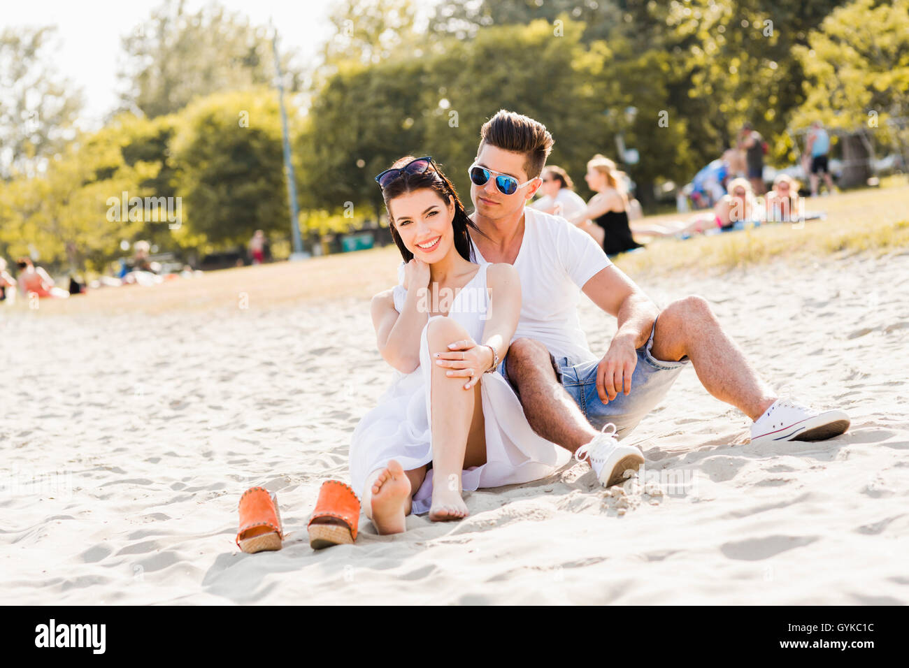 Couple amoureux assis à une plage de sable fin et souriant Banque D'Images