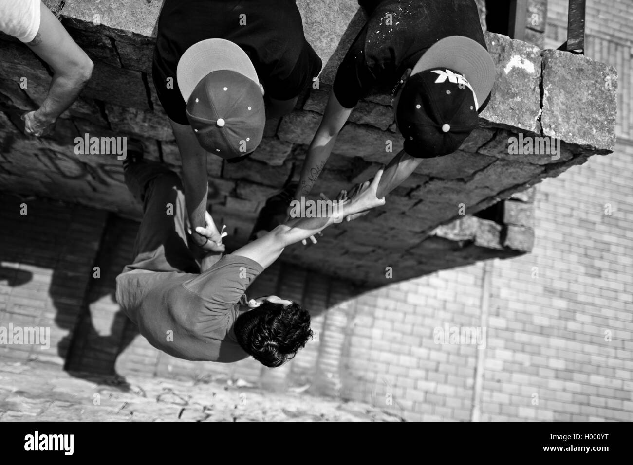 Un parkour runner, suspendu à ses copains' hands, grimpe sur le mur pendant une session de formation à Bogotá, Colombie. Banque D'Images