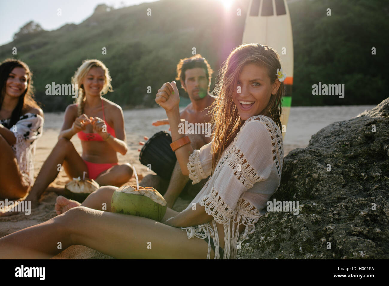 Excitée jeune femme s'amusant sur la plage avec ses amis dans l'arrière-plan. Groupe d'amis profitant de vacances d'été sur le bea Banque D'Images