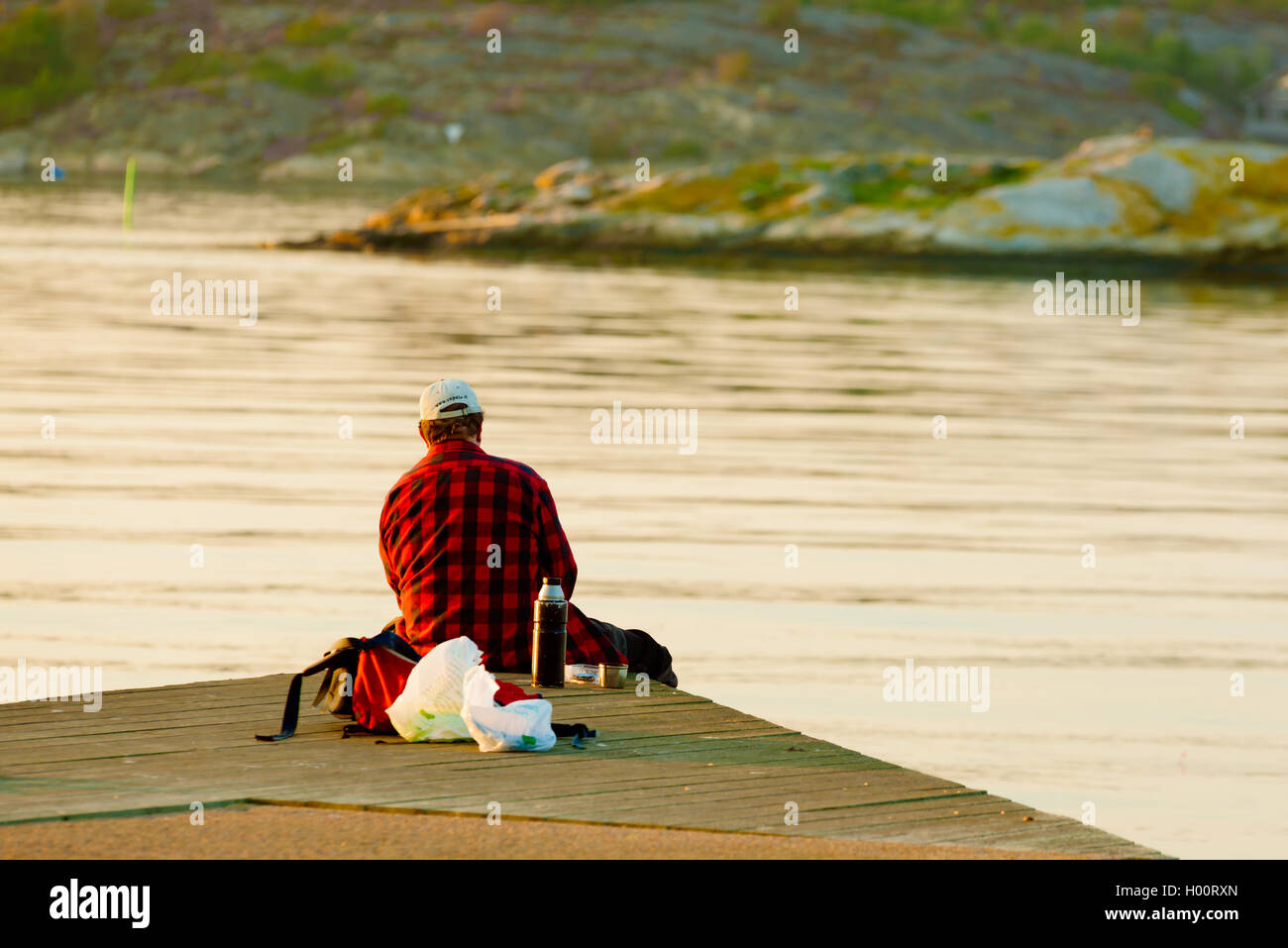 Marstrand, Suède - septembre 8, 2016 : Film d'un homme vu de dos sitting on pier looking at view pendant la pêche. E Banque D'Images