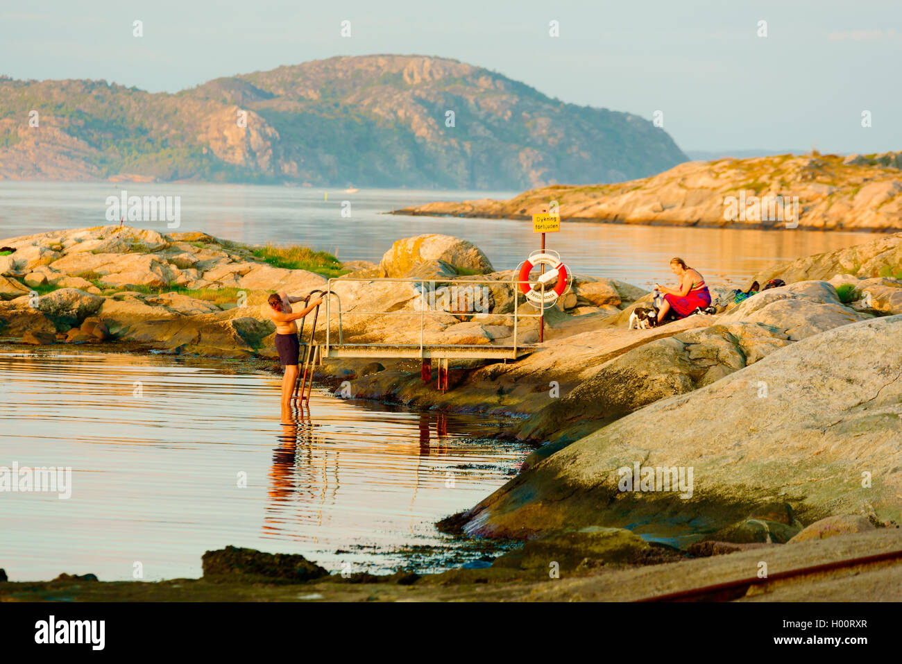 Marstrand, Suède - septembre 8, 2016 : Documentaire d'hommes descendre une échelle pour prendre une courte soirée nager dans l'océan whil Banque D'Images