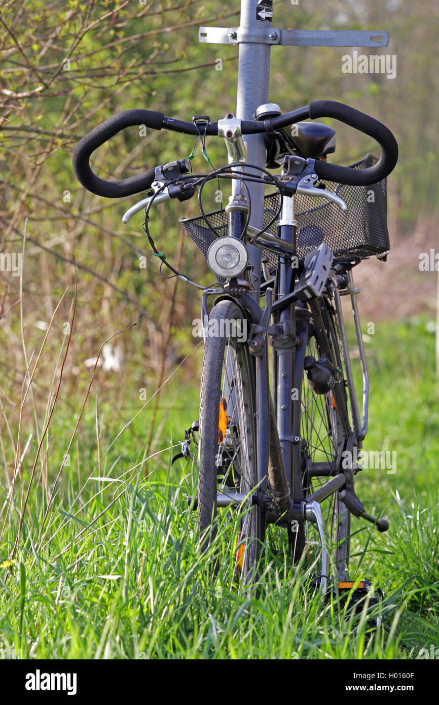 Vélo en stationnement dans l'herbe verrouillé à un pôle signe, Allemagne Banque D'Images