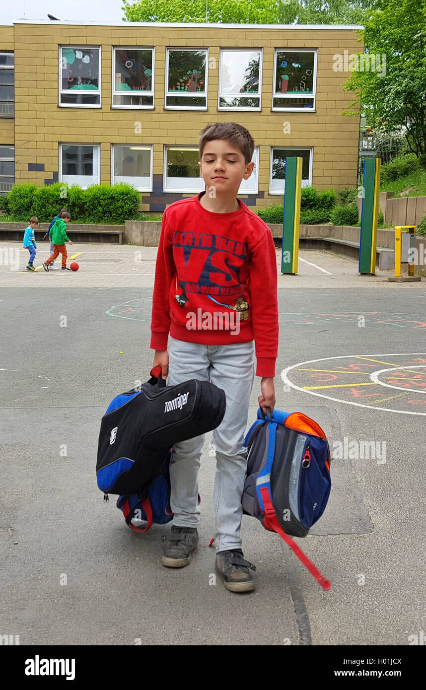 Épuisé garçon debout après fin de l'école avec sacoche et guitare sur la cour de l'école Banque D'Images