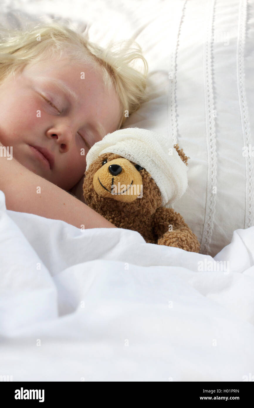 Une jeune fille mal dans le lit de câliner son nounours qui se sent mal. Banque D'Images