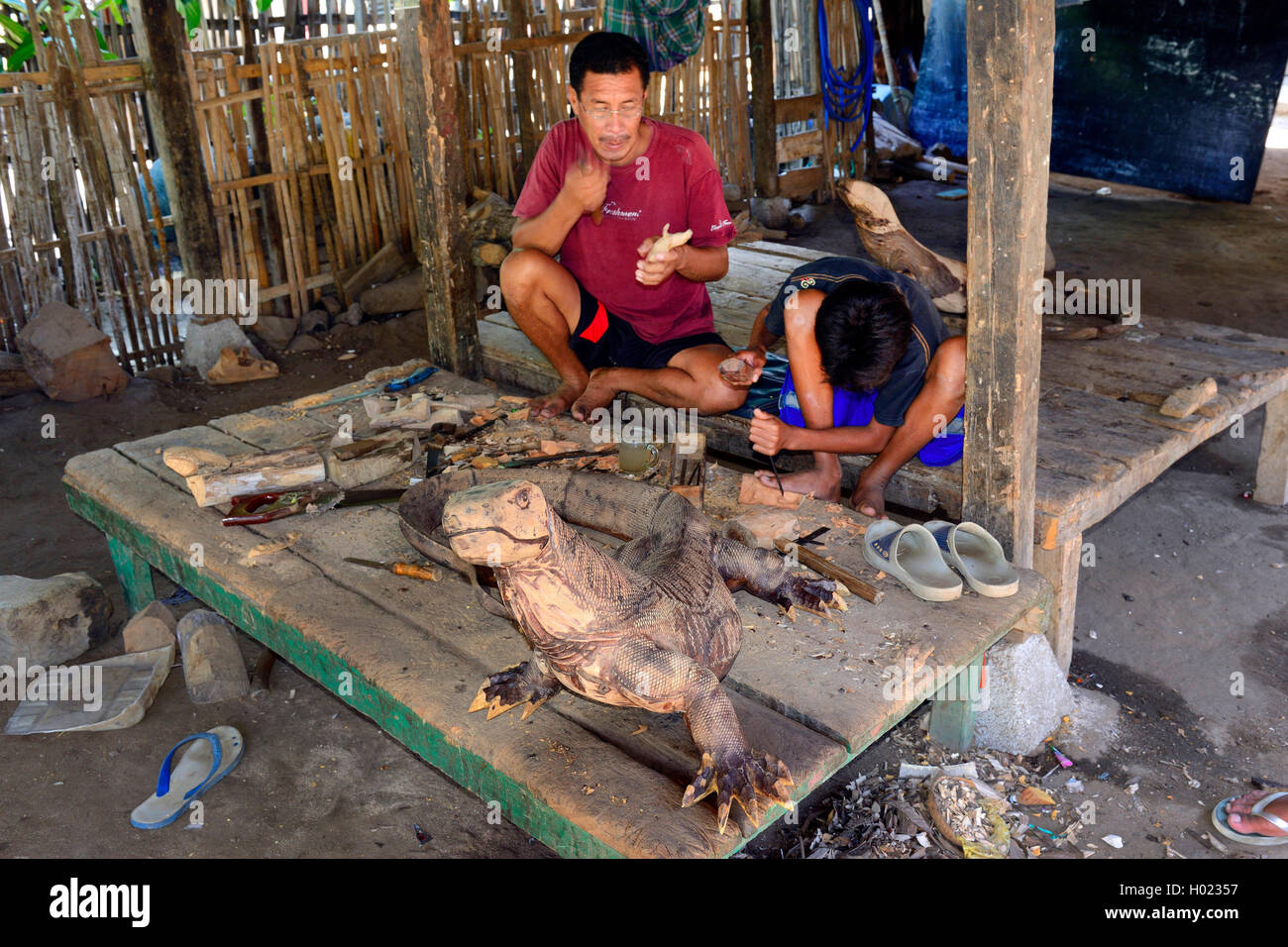 Vater und Sohn unter schnitzen Komodowarane in Ihrem Haus, Indonesien, île de Komodo Komodo, Nationalpark | père et fils scarving Banque D'Images