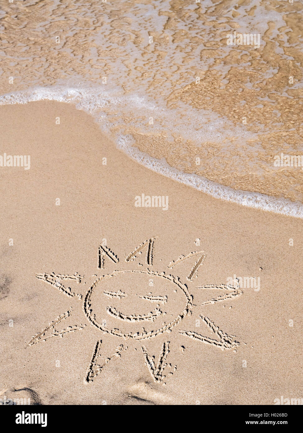 Doigt dessiné soleil sur plage de sable Banque D'Images