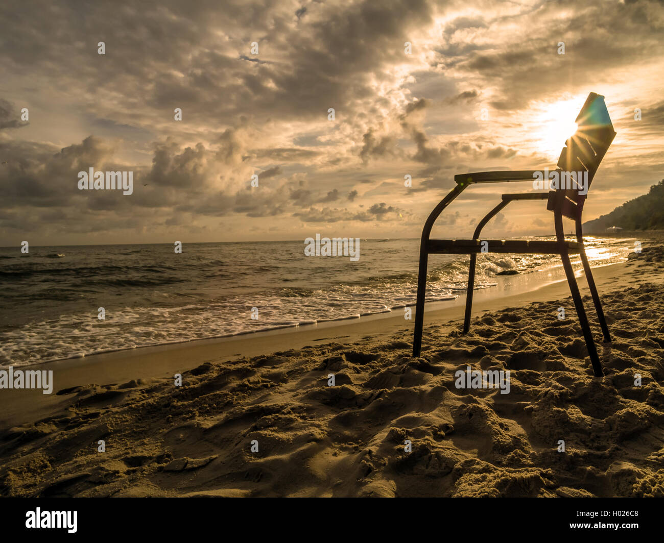 Silhouette de fauteuil en bois contre le soleil levant à la plage Banque D'Images