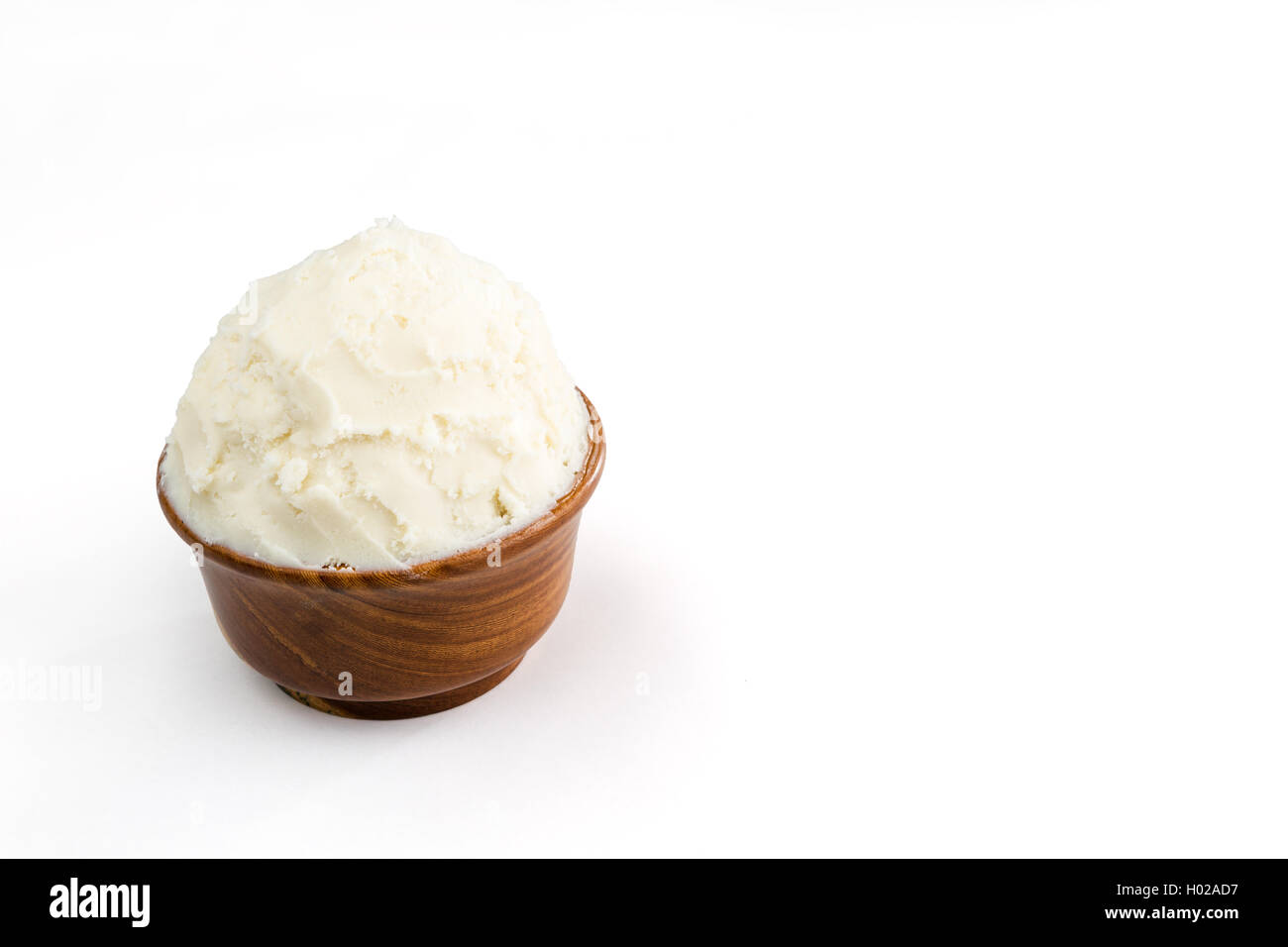Beurre de karité bio non raffinée, dans le bol en bois debout sur le fond blanc pur. Banque D'Images