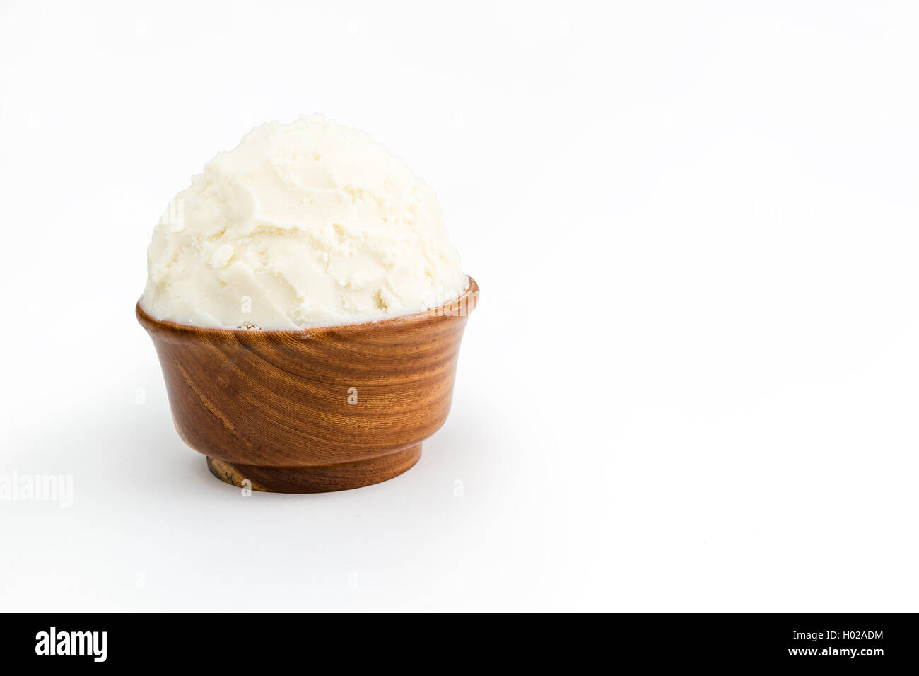 Beurre de karité bio non raffinée, dans le bol en bois debout sur le fond blanc pur. Banque D'Images
