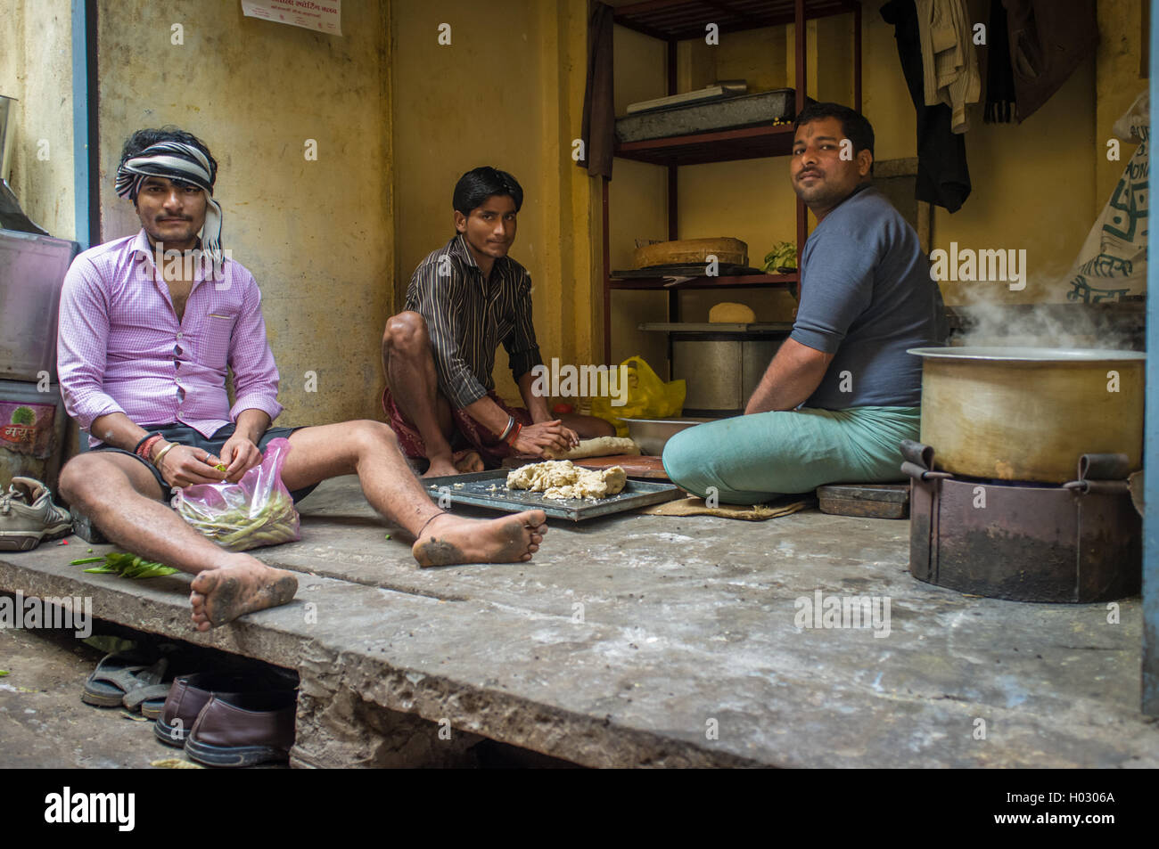 VARANASI, INDE - 20 février 2015 : trois jeunes hommes adultes s'asseoir sur le sol et préparer le déjeuner dans la cuisine simple. Banque D'Images