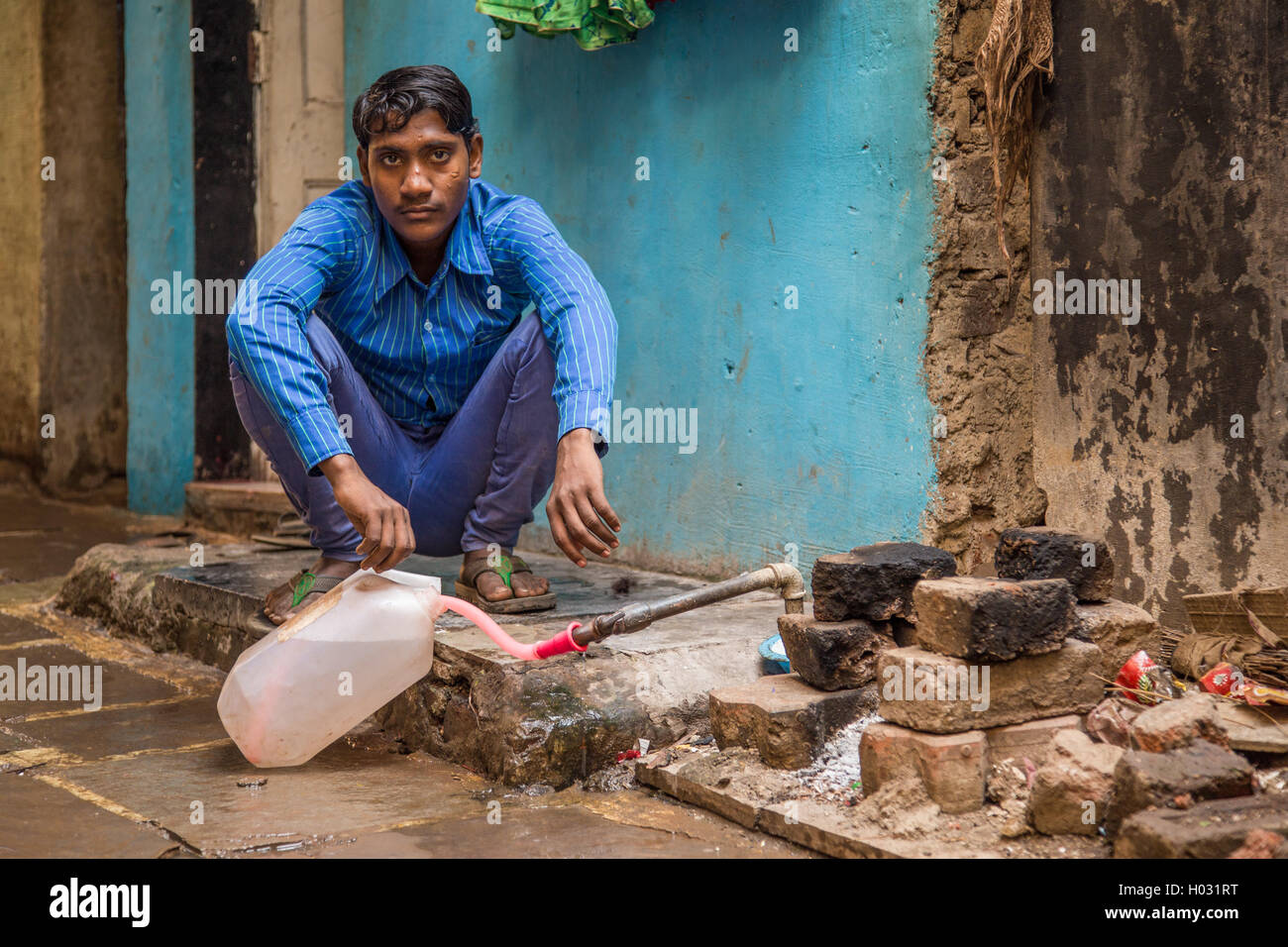 MUMBAI, INDE - 12 janvier 2015 : Jeune Indien homme est assis et remplit le réservoir d'eau dans la rue. La plupart des bidonvilles Dharavi a bande potable wa Banque D'Images