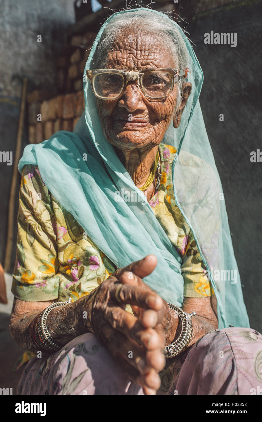 Région GODWAR, INDE - 13 février 2015 : personnes âgées femme indienne en sari avec tête couverts et verres réparé est assis dans la porte de Banque D'Images
