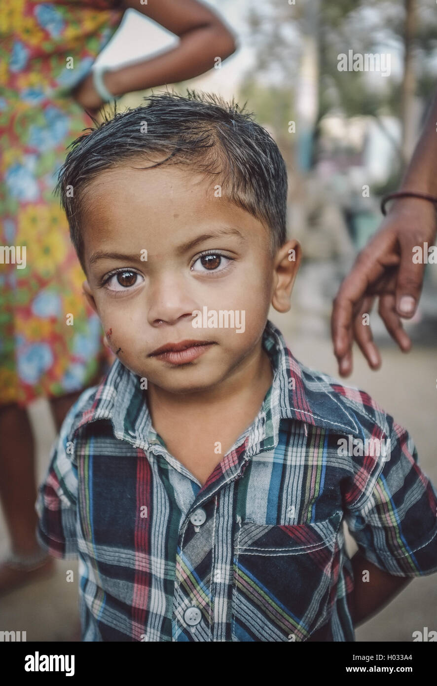 HAMPI, INDE - 31 janvier 2015 : jeune Indien en chemise colorée avec les membres de la famille en arrière-plan. Post-traités avec grain, textu Banque D'Images